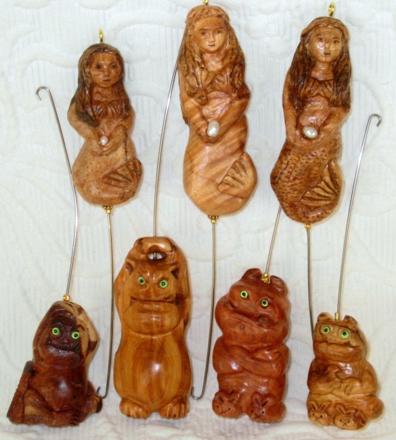 MERMAIDS carrying freshwater pearls.  L-to-R: mystery wood.  Curly maple. Spalted maple. GREMLINS:  Thuya wood.  Yew.  Madrone burl.  Yew.